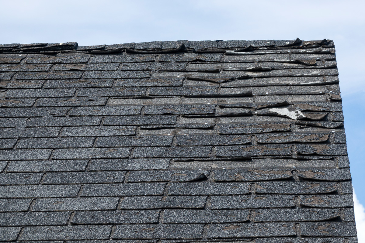 A roof with missing and damaged shingles in El Paso.