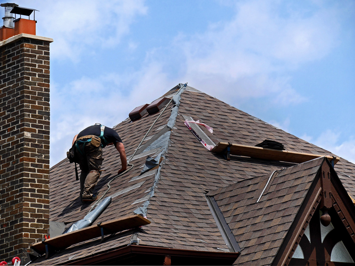 A person on a home’s roof performing roof repair in El Paso.